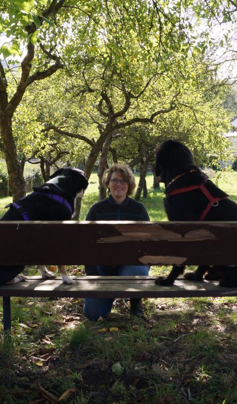 Eva mit zwei Hunden auf einer Bank im Park